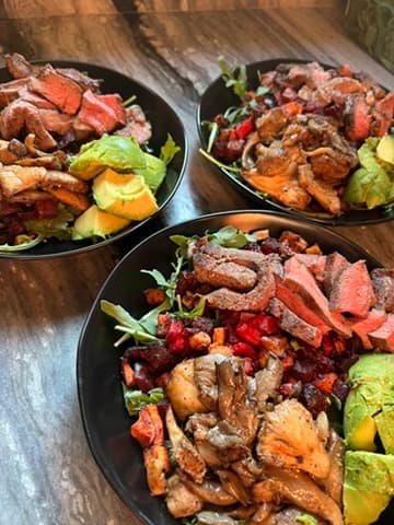 Plated bowls with steak, avocado, and roasted vegetables